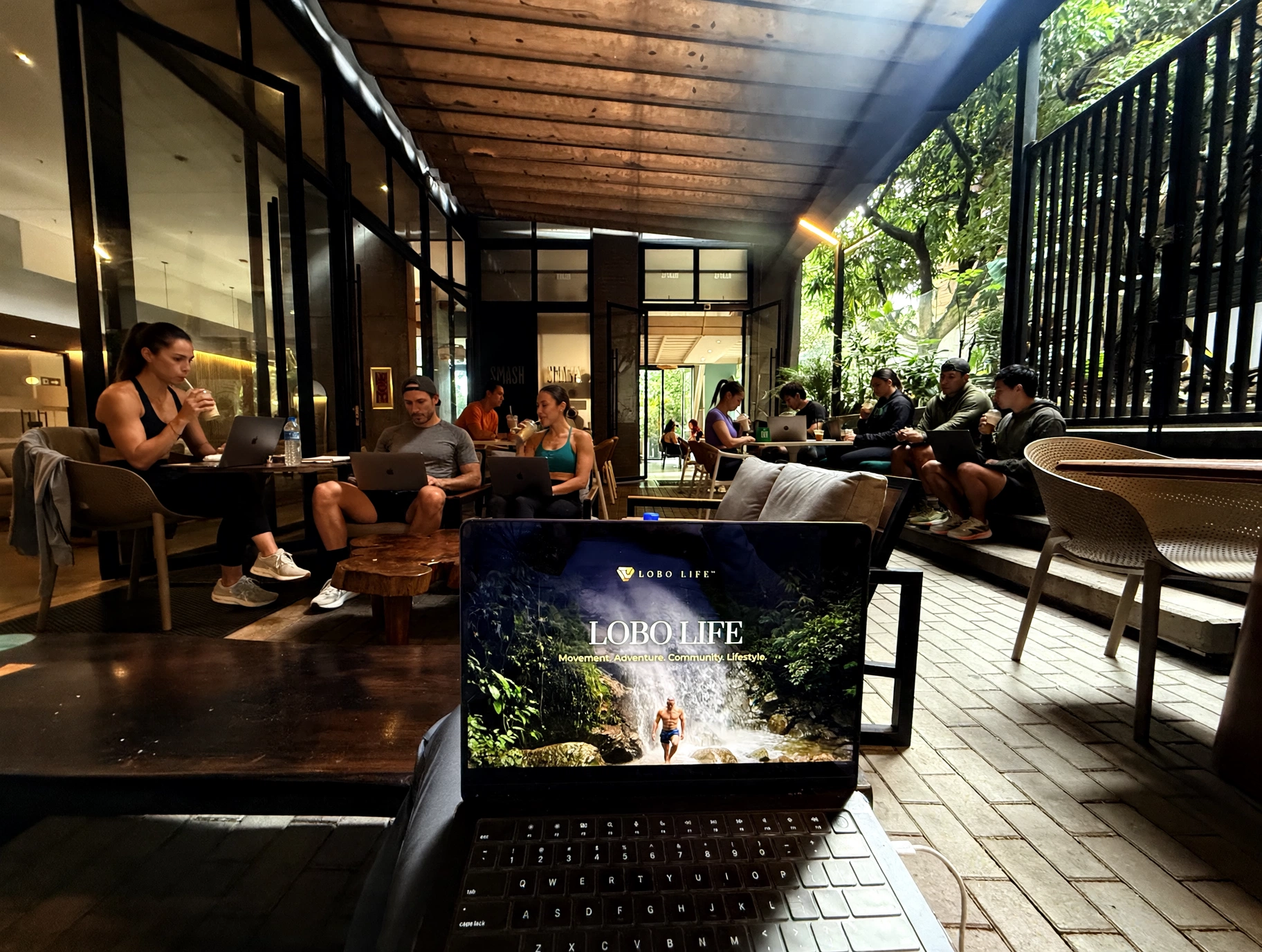 Lobo Living™ members — men and women — working and connecting at an open-air café in Medellín